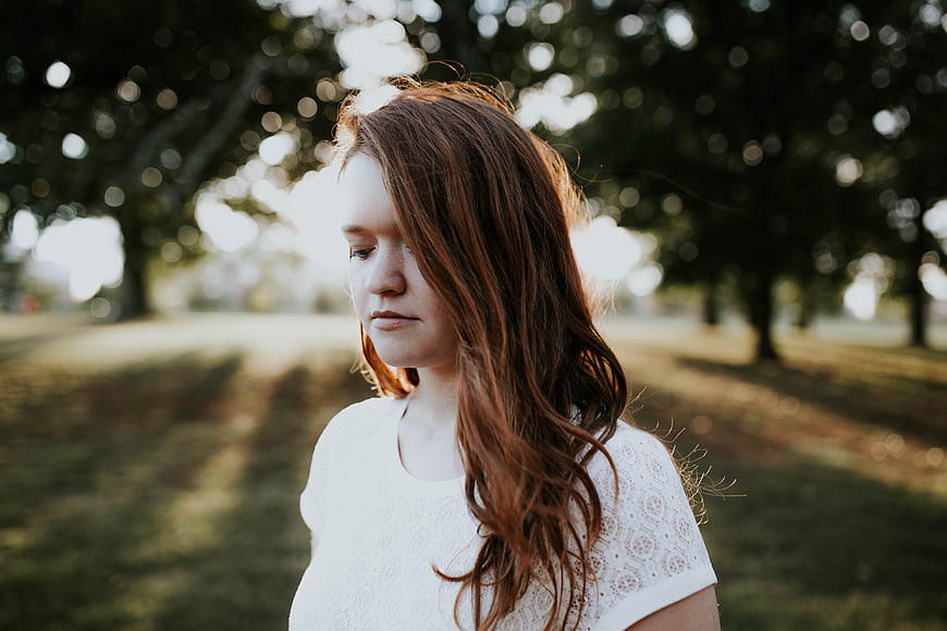 Pensive Young Woman with Red Hair in Park