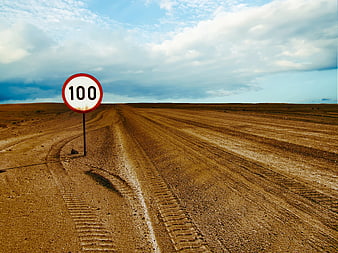Speed limit sign 100 on dusty desert road