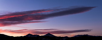 Dramatic sunset over snow-capped mountain peaks with vibrant clouds