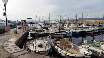 Boats docked in a Mediterranean harbor with mountains in background