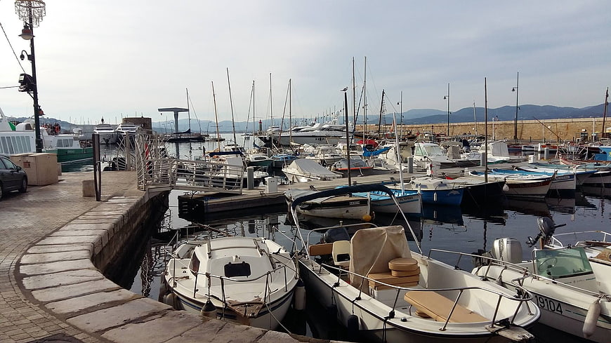 Boats docked in a Mediterranean harbor with mountains in background