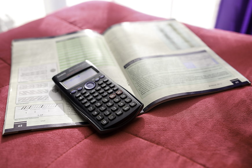 Scientific calculator on open textbook on red fabric