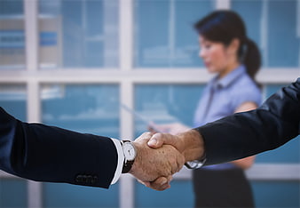 Business handshake in office with blurred female executive background