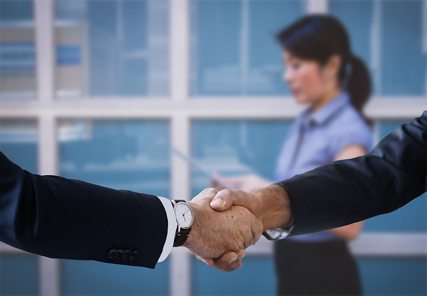 Business handshake in office with blurred female executive background