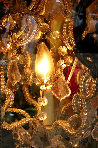 Close-up of glowing crystal chandelier with candle-style bulb