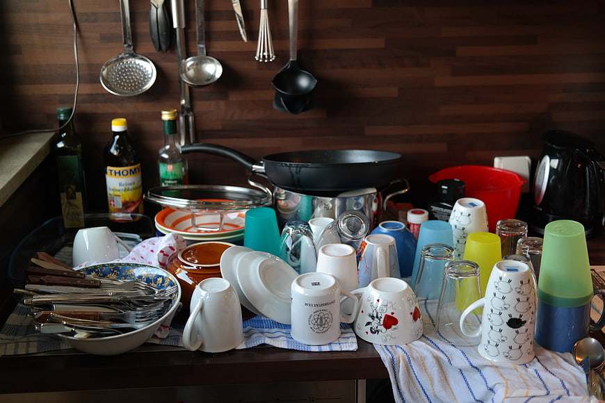 Pile of dirty dishes and cutlery on kitchen counter