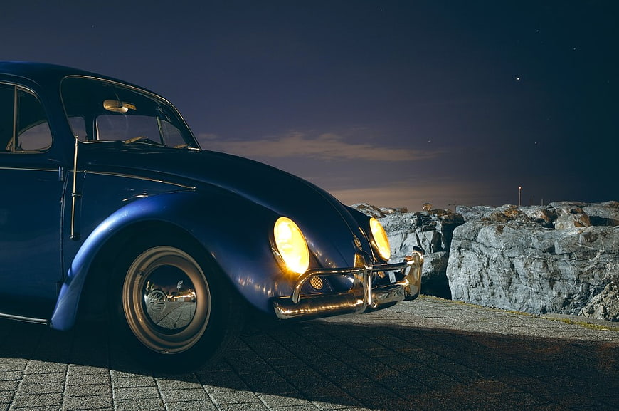 Blue VW Beetle with Headlights On at Night