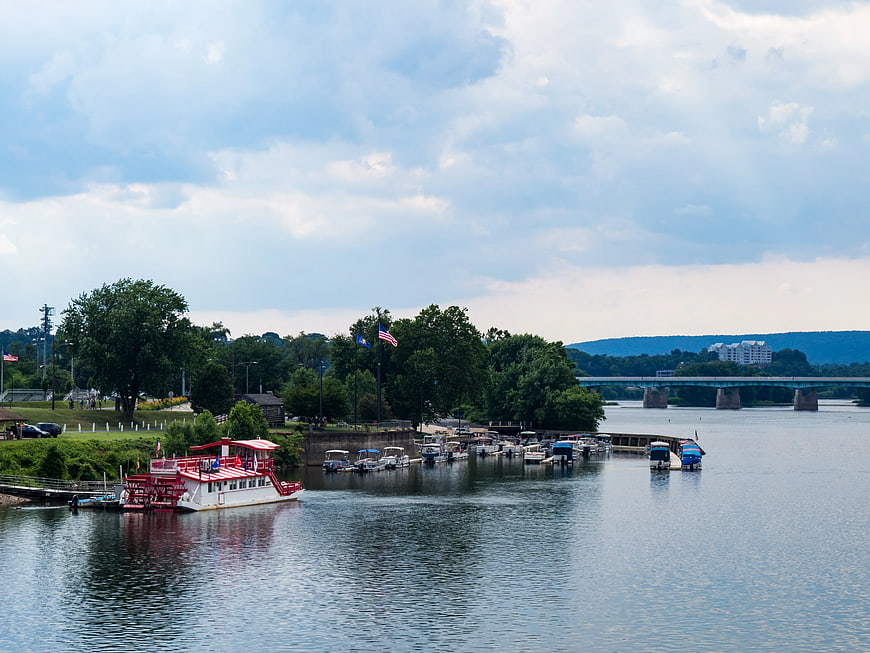 Red and white paddle boat docked at marina with bridge
