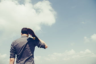 Man with Skateboard Looking at Blue Sky with Clouds