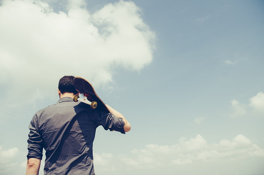 Man with Skateboard Looking at Blue Sky with Clouds