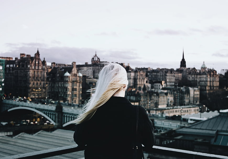Woman with blonde hair looking at Edinburgh city skyline