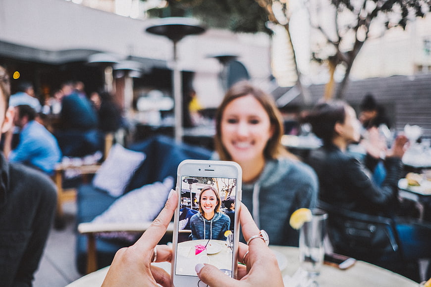 Woman taking photo of friend at outdoor cafe