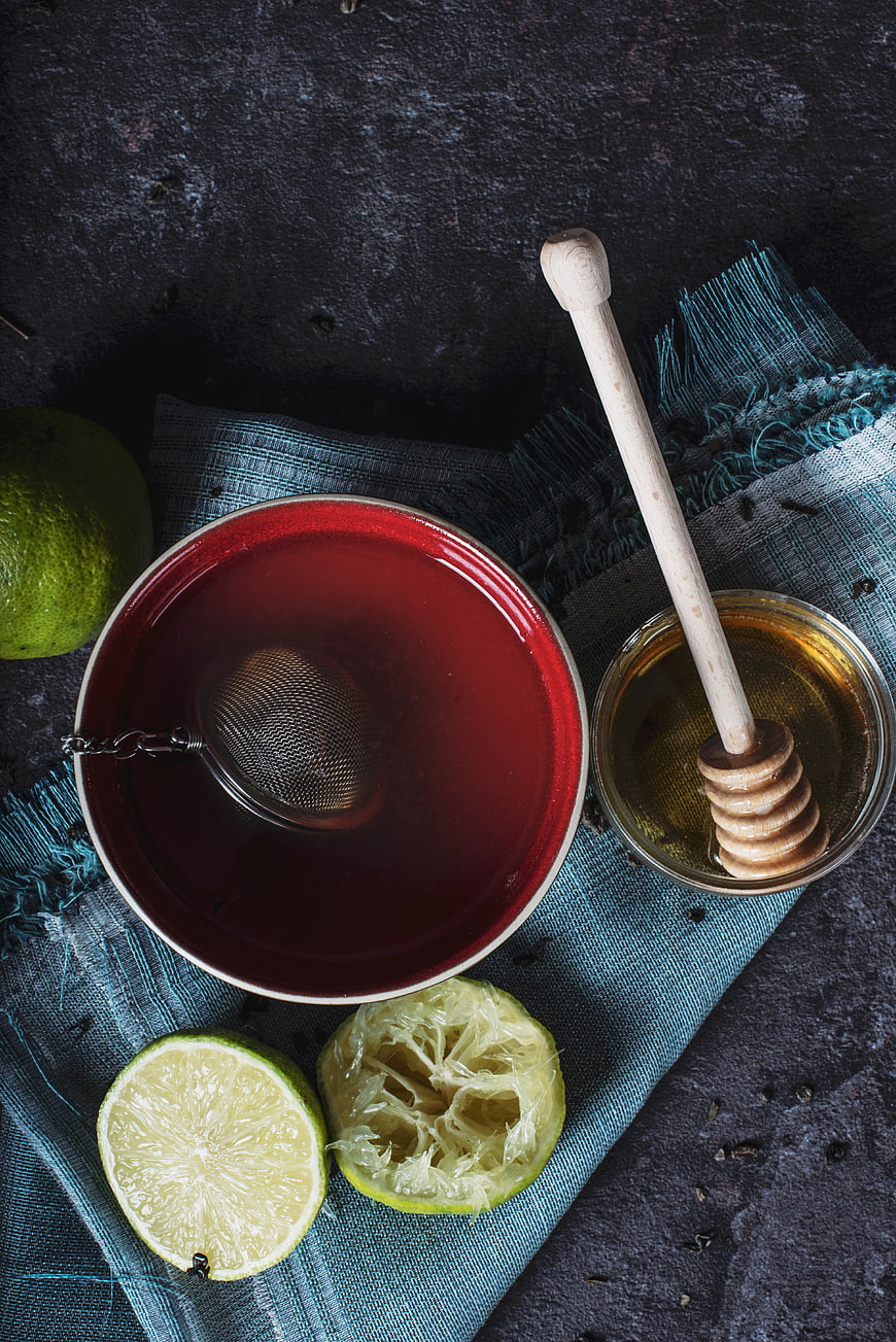 Overhead view of hot tea with honey and lime on dark background