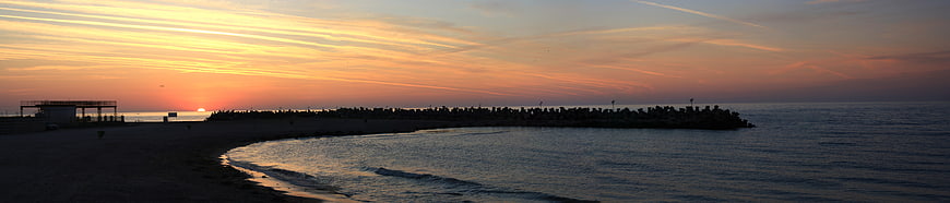 Panoramic Sunrise Over Beach Breakwater Silhouette