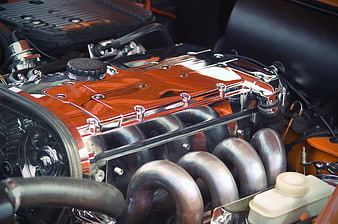 Close-up of polished chrome classic car engine with orange valve cover