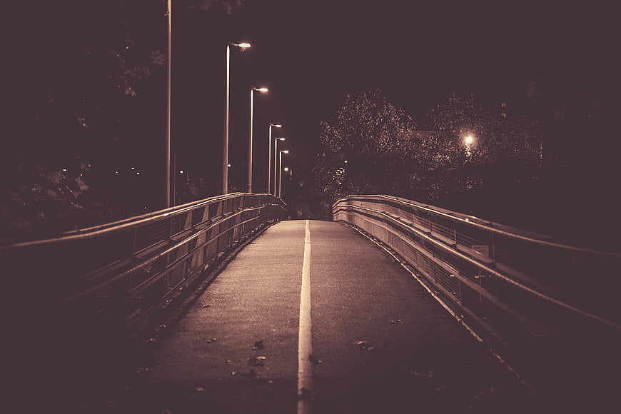 Empty bridge at night with streetlights and yellow line