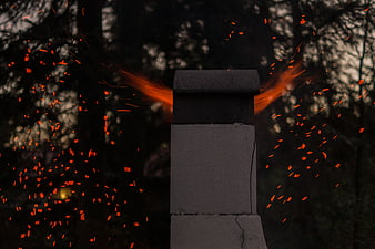 Sparks flying from chimney against dark forest background