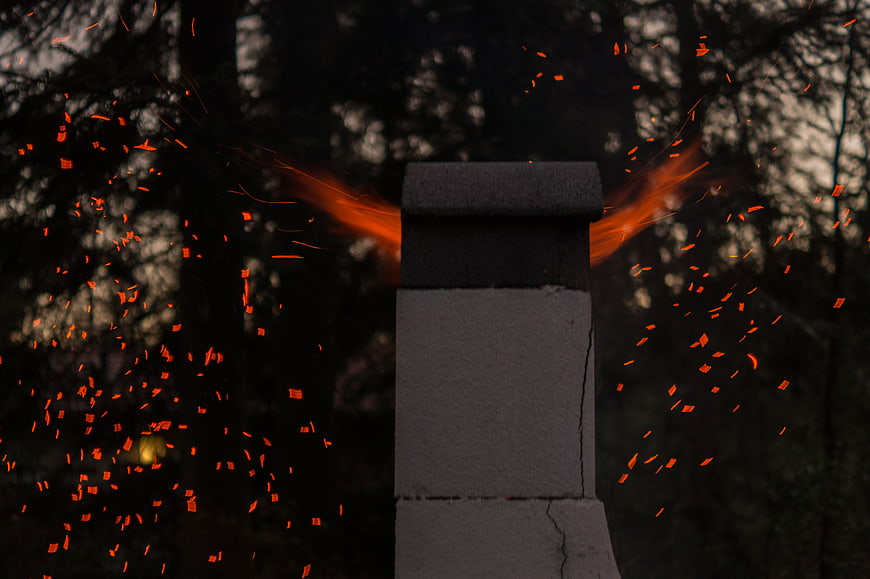 Sparks flying from chimney against dark forest background