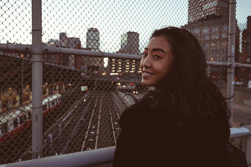 Smiling Asian Woman on Urban Bridge at Dusk