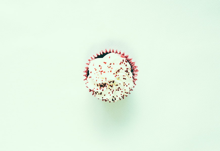 Top-Down View of Single Frosted Cupcake with Sprinkles on Mint Background