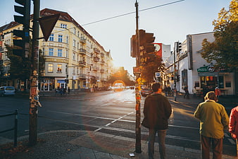 Pedestrians waiting at city intersection during golden hour