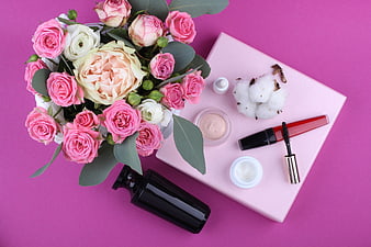 Pink roses and beauty products flat lay on magenta background