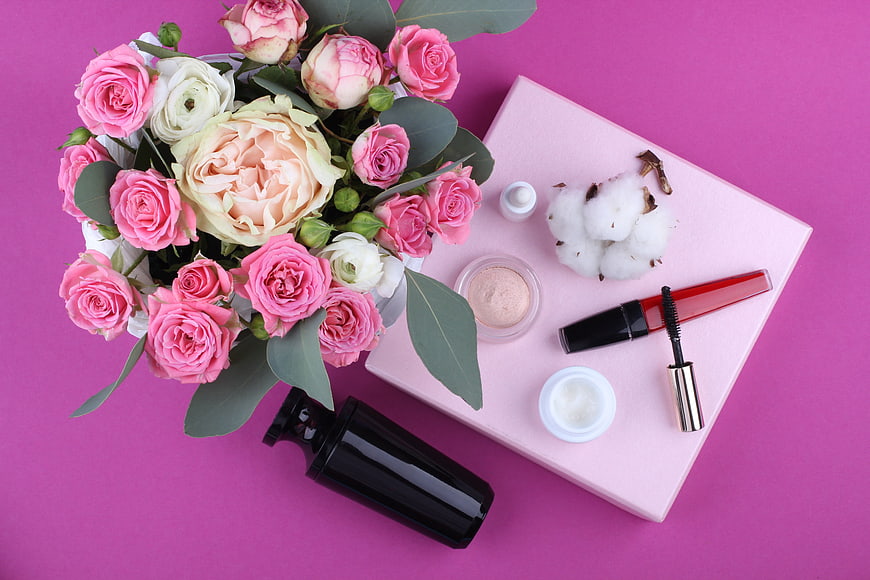 Pink roses and beauty products flat lay on magenta background