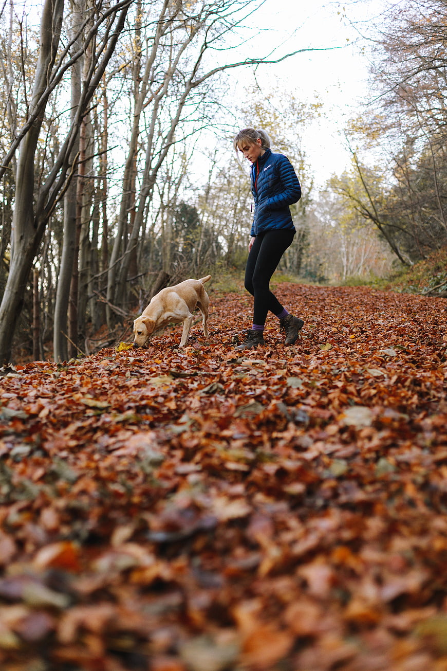 Woman hiking with dog on autumn forest path