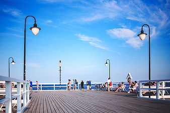 People relaxing on a sunny wooden pier by the sea
