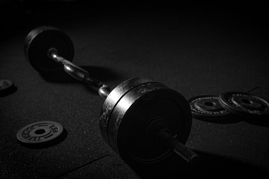 Black and white dumbbell with weight plates on gym floor