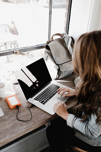 Woman working on laptop in cafe by window