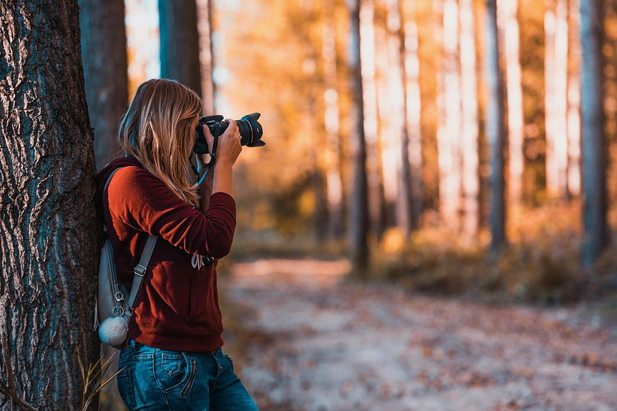 Female Photographer Taking Pictures in Autumn Forest