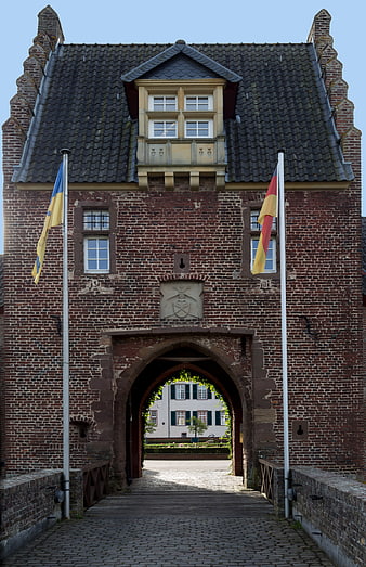 Historic Brick Gatehouse with Flags and Cobblestone Bridge