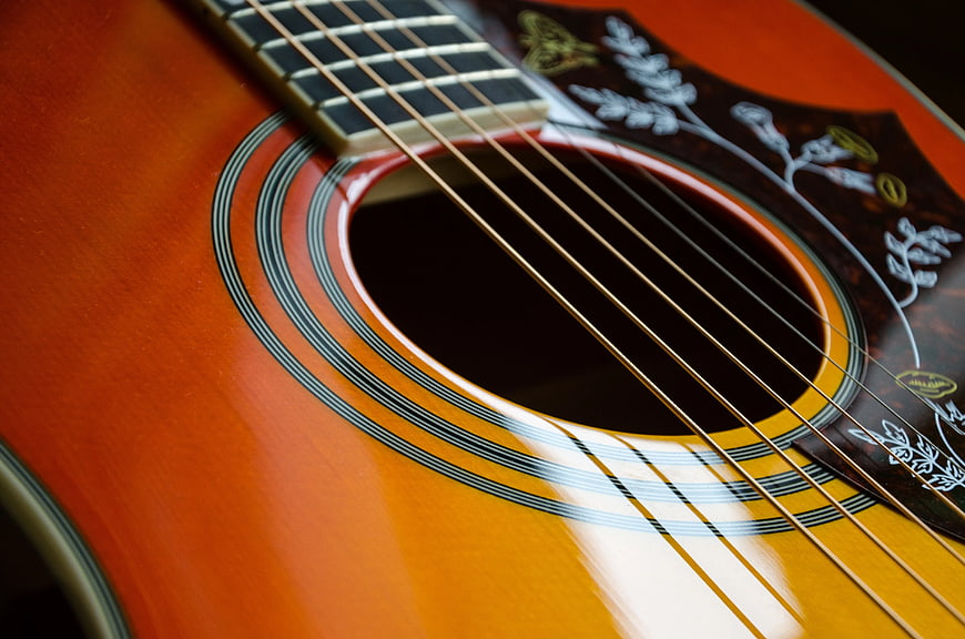 Close-up of acoustic guitar body with floral pickguard