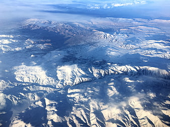 Aerial View of Snow-Covered Mountain Range with Clouds