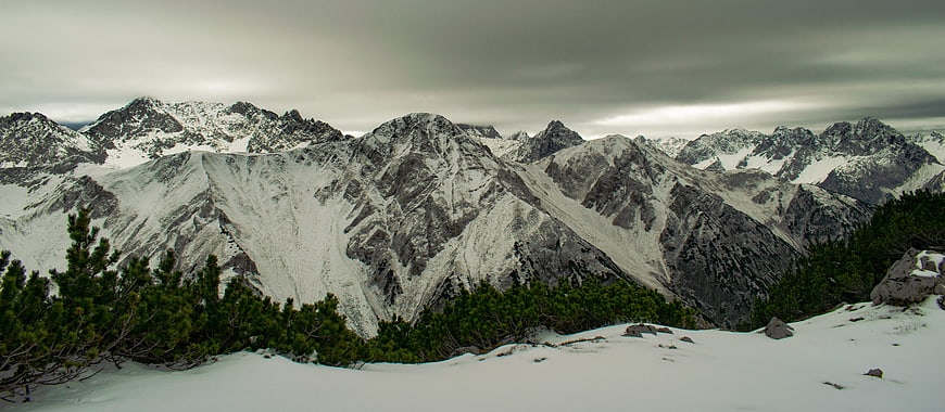 Panoramic view of snow-covered mountain peaks under cloudy sky