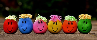 Row of colorful stress balls with smiley faces and yarn hair