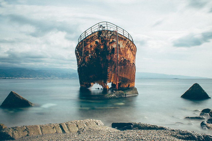 Rusty Shipwreck in Calm Sea with Concrete Tetrapods