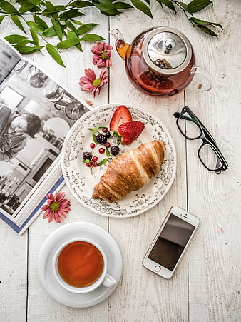 Top view of breakfast with croissant, tea, and book
