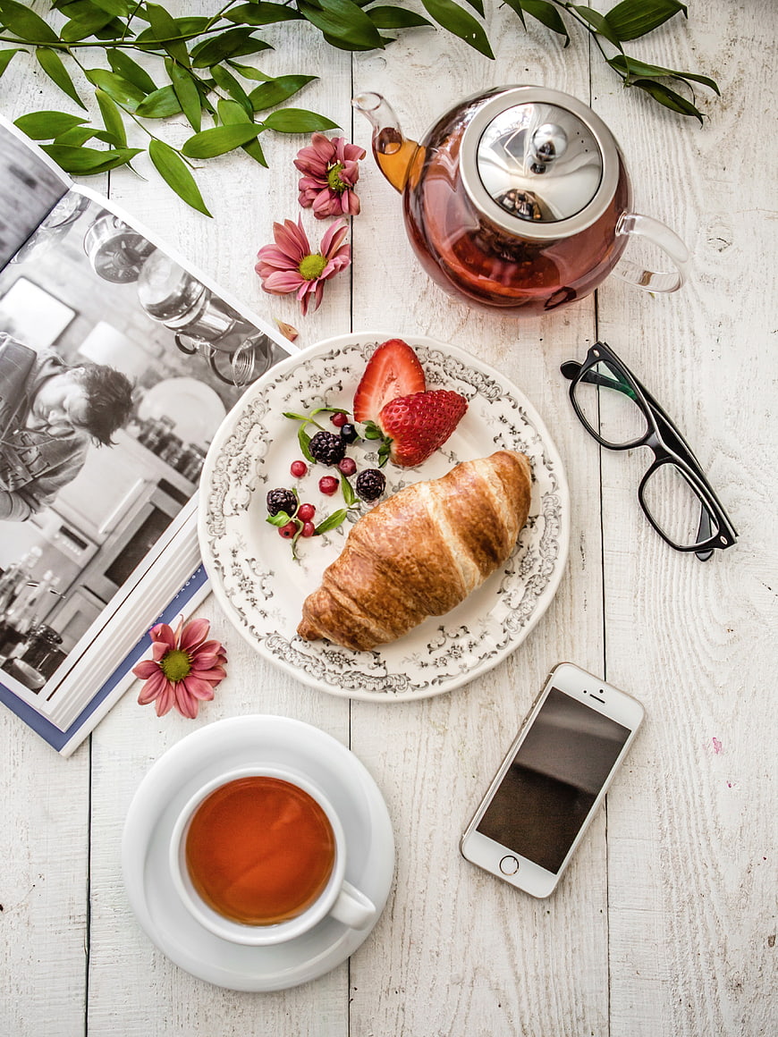 Top view of breakfast with croissant, tea, and book