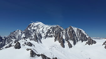 Aerial View of Snow-Covered Mountain Peaks Under Blue Sky