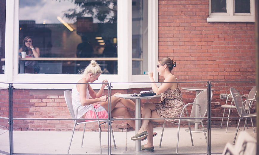Two women chatting at outdoor cafe table