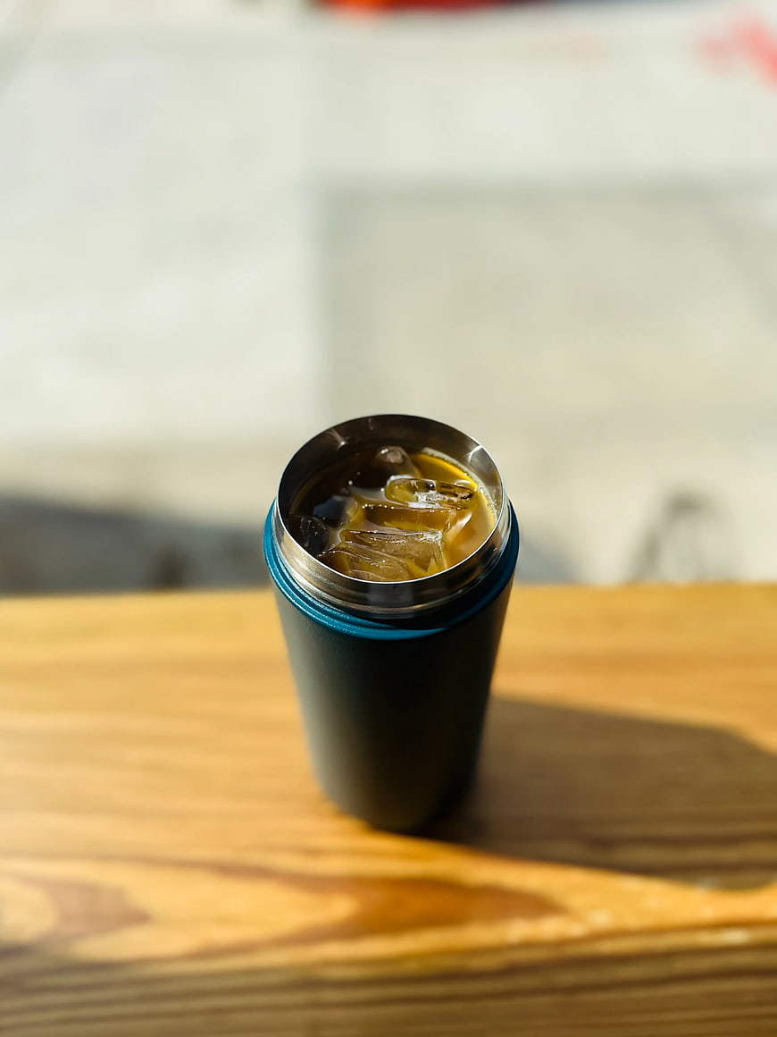 Iced Coffee in Black Travel Mug on Wooden Table