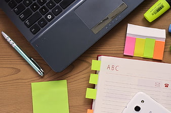 Top view of laptop, notebook, and office supplies on wooden desk