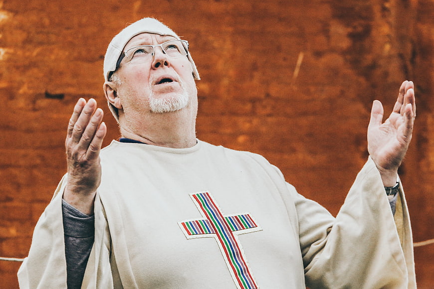 Senior Priest Praying with Raised Hands in Church Vestments