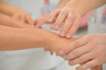 Doctor checking patient pulse with hands close up