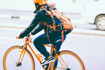 Cyclist Riding Orange Bike with Backpack on City Street