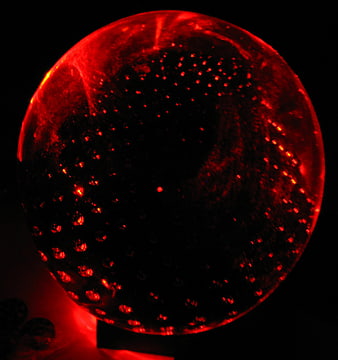 Glowing red glass sphere with bubble texture on black background