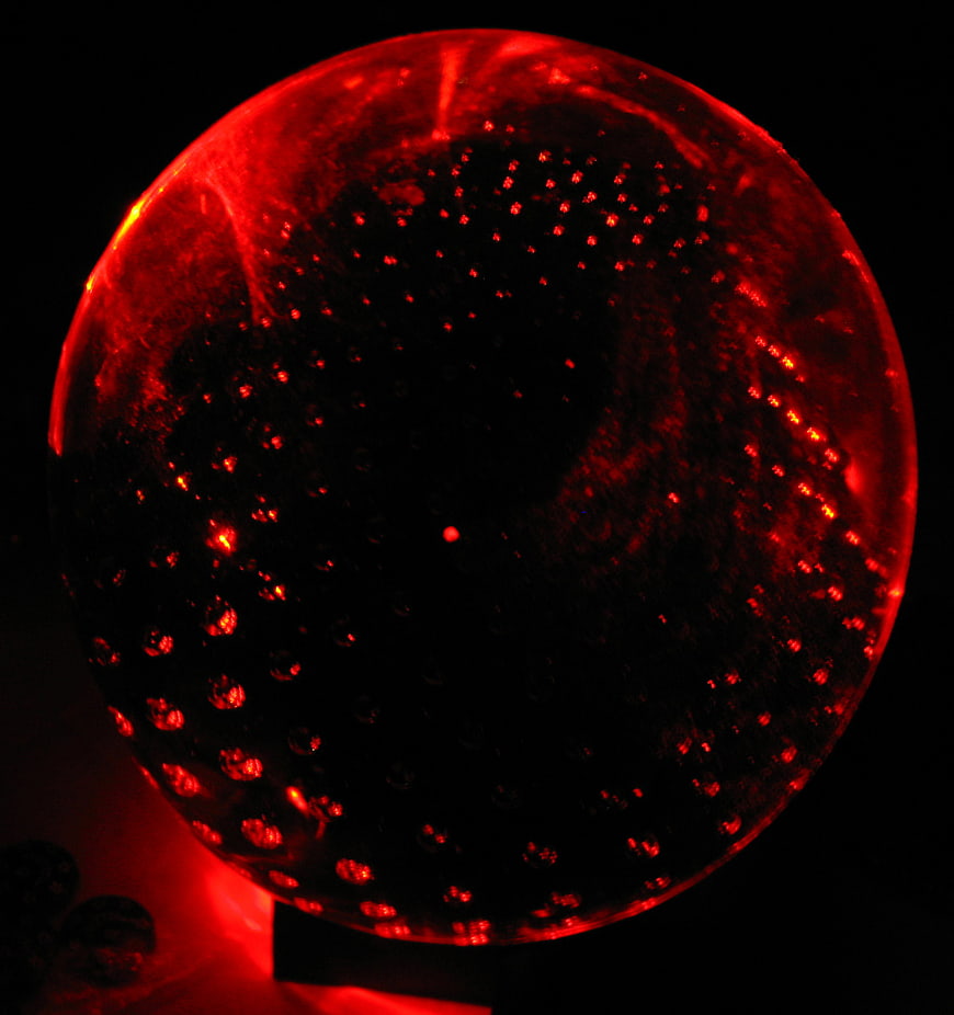 Glowing red glass sphere with bubble texture on black background