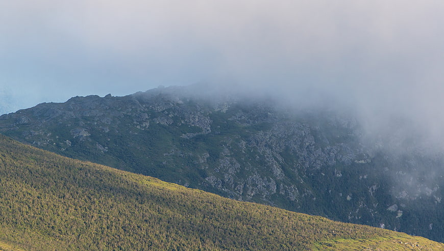 Misty Mountain Ridge with Sunlit Forest Slope